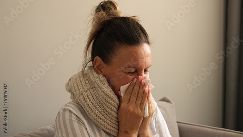 Sick woman wrapped in scarf coughing sneezing battling virus Shows symptoms of virus seeking relief Home care for virus evident in her discomfort Virus symptoms highlight need for rest and recovery