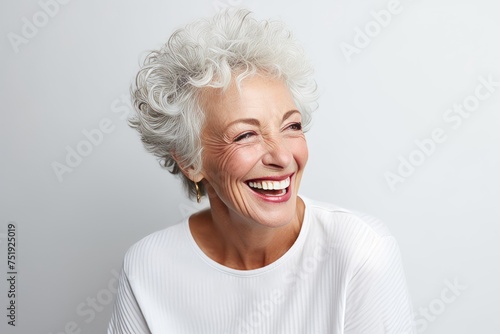 Portrait of happy senior woman laughing against white background. Looking at camera.