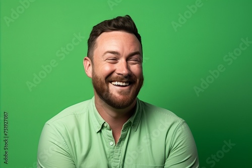 Portrait of a funny man laughing on a green background. Studio shot.