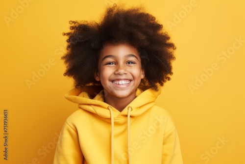Portrait of cute african american little girl in yellow hoodie on yellow background