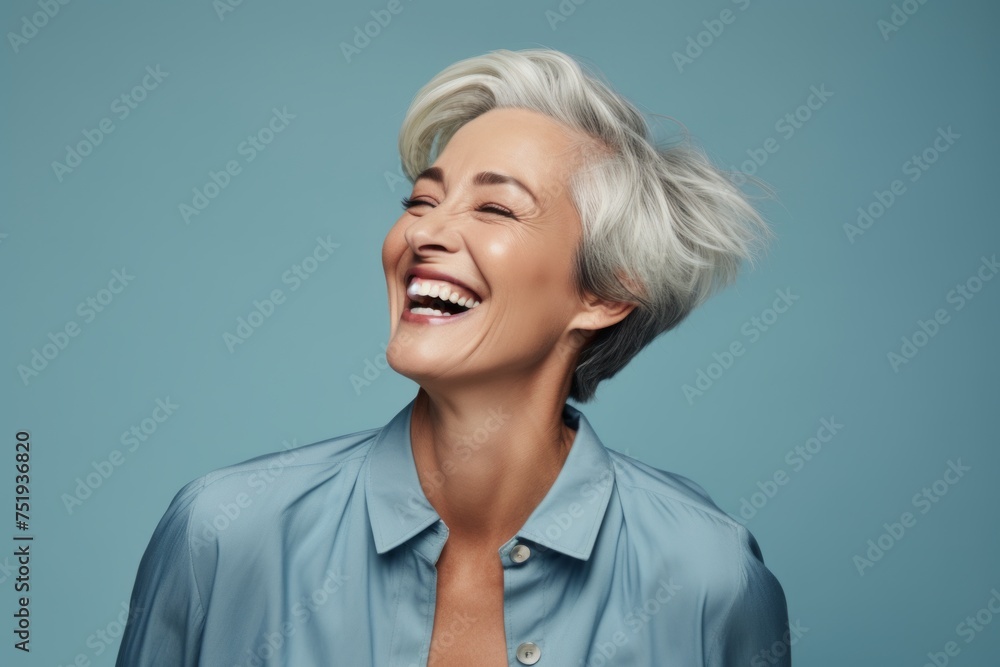 Beautiful mature woman with short grey hair laughing on a blue background Beautiful mature woman with short grey hair laughing on a blue background