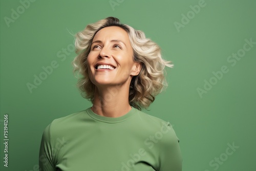 smiling middle aged woman in green sweater looking up on green background