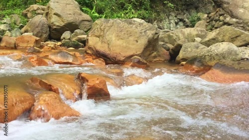 Follow the water from the waterfall downstream in Pulangbato Falls. The area around the waterfall in Valencia on the Negros Oriental Island. Many plants grow among the rocks on the shore. photo