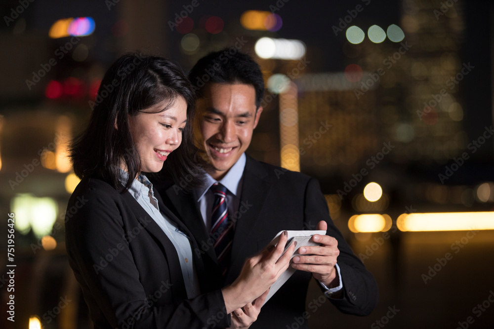 Asian Business people using tablet in city at night.