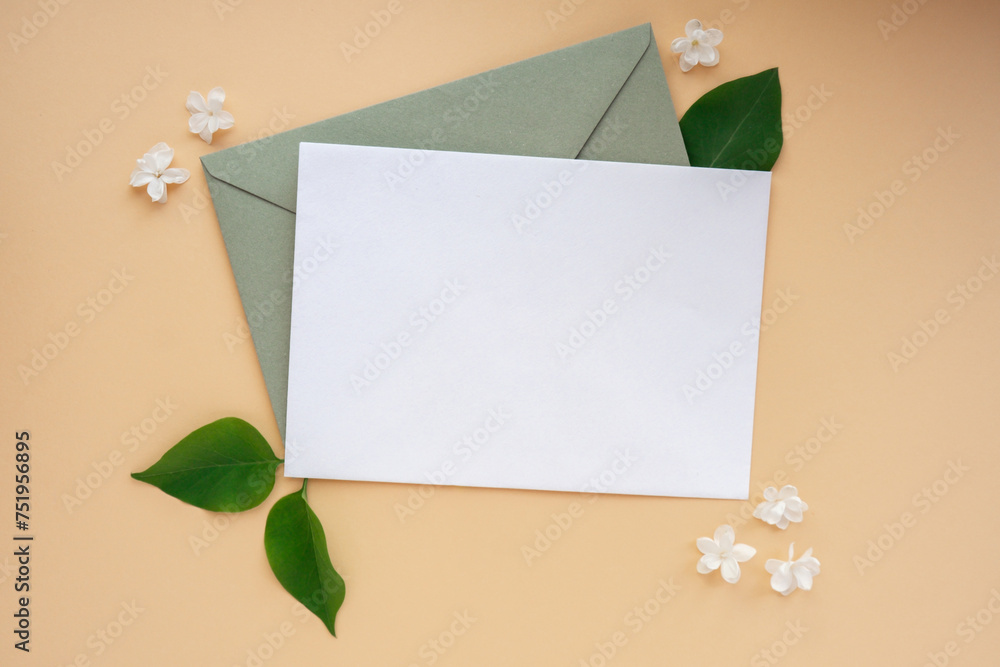 Composition with empty envelope and beautiful spring lilac flowers on beige background. Mockup card invitation greeting card postcard copy space template. Branches of lilac blooming bouquet.