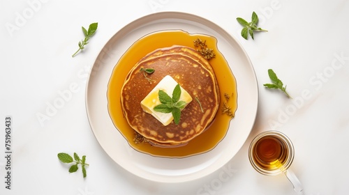 Plate of corn and whole wheat pancakes topped with cultured butter and Vermont maple syrup, arranged on a white round plate, displayed against a white background in an aerial view