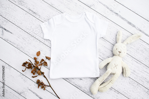 Blank baby bodysuit half mock up on wood background with dried flowers and toy