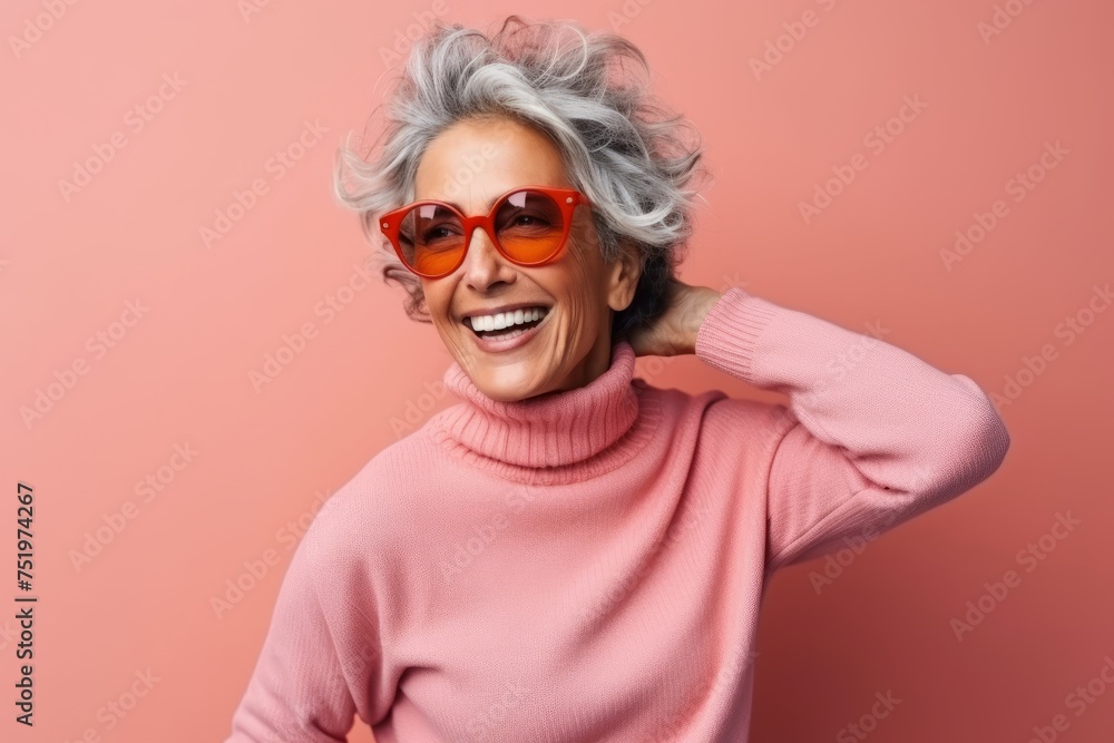 Cheerful senior woman with grey hair wearing pink sweater and sunglasses
