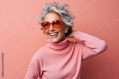 Cheerful senior woman with grey hair wearing pink sweater and sunglasses © Iigo