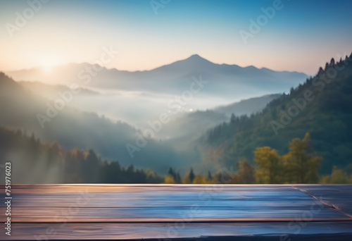 Serene sunrise over misty mountains with a smooth wooden surface in the foreground.