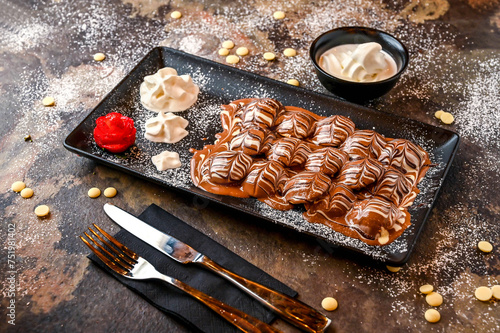 Marble Poffers with chocolate, whipped cream, knife and fork served in dish isolated on dark background closeup top view of cafe baked dessert food photo