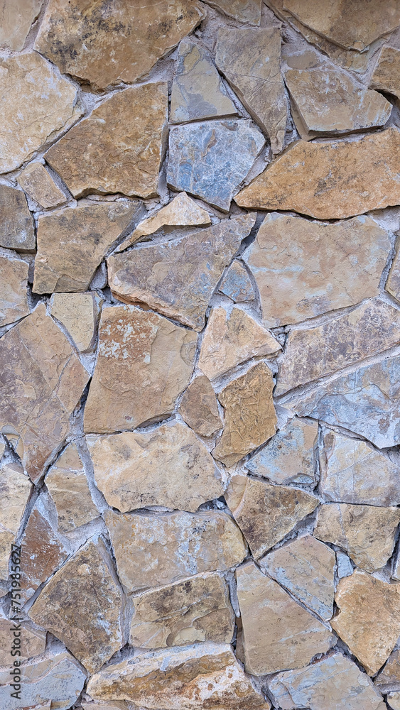 Irregular rustic stone and cement wall texture or background. Exterior wall cladding with mediterranean stones of different colors. Irregular rustic stone and cement wall texture or background. Exterior wall cladding with mediterranean stones of different colors.