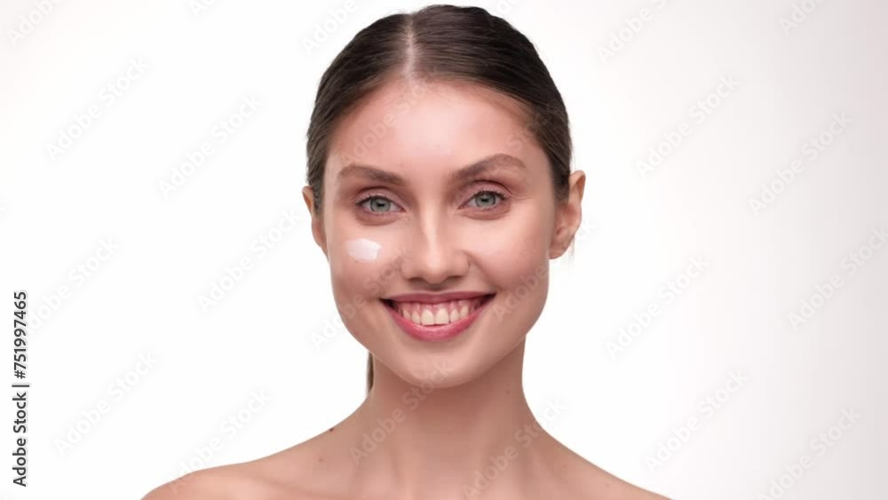 Female beauty procedures. Lady cream applying smear of pampering cream on her cheek and smiling to the camera, white studio background. Skin care concept. Cosmetic Concept. Female beauty procedures. Lady cream applying smear of pampering cream on her cheek and smiling to the camera, white studio background. Skin care concept. Cosmetic Concept.