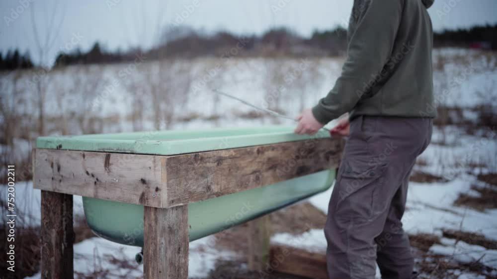 The Man is Utilizing a Collapsible Yardstick to Measure the Dimensions of the Homemade Hot Tub - Static Shot The Man is Utilizing a Collapsible Yardstick to Measure the Dimensions of the Homemade Hot Tub - Static Shot