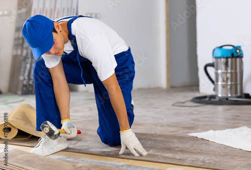 Professional male builder laying laminate flooring in a room being renovated