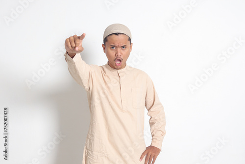 Portrait of attractive Asian muslim man in koko shirt making angry hand gesture with fingers, scolding someone who has done something wrong. Isolated image on white background