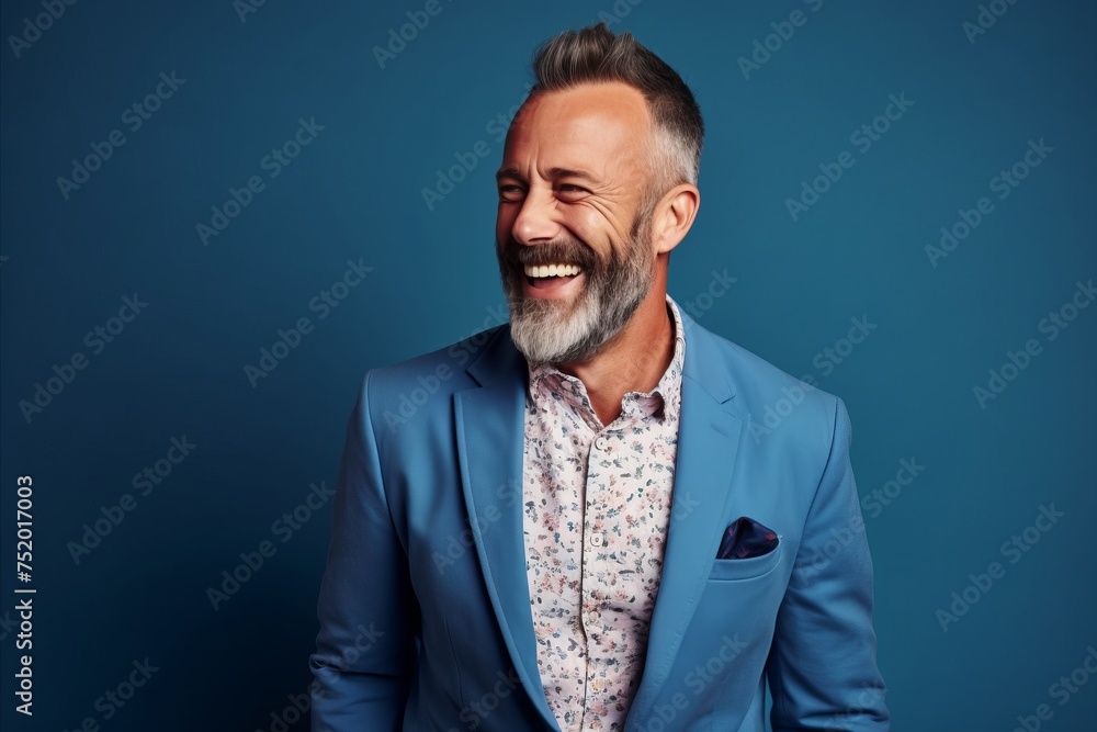 Portrait of a happy senior man laughing against blue background. Men's beauty, fashion.