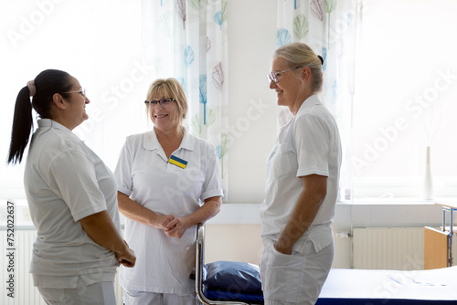 Smiling female doctors discussing with each other in ward at hospital photo