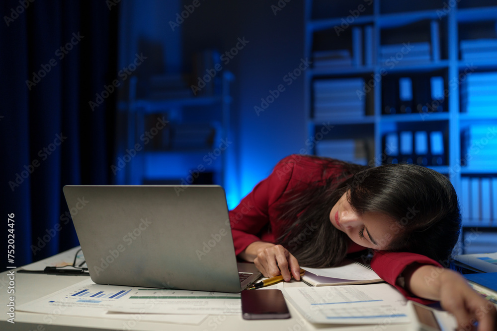 Asian businesswoman is tired, sleepy and bored from sitting at a desk for a long time working on a laptop computer. Problematic financial paperwork Office syndrome concept. Asian businesswoman is tired, sleepy and bored from sitting at a desk for a long time working on a laptop computer. Problematic financial paperwork Office syndrome concept.