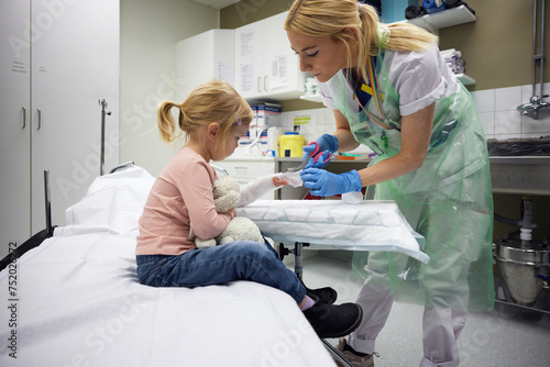 Female orthopedic tying bandage on girl's hand in hospital