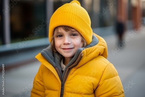 Portrait of cute little girl in yellow winter jacket and hat outdoors