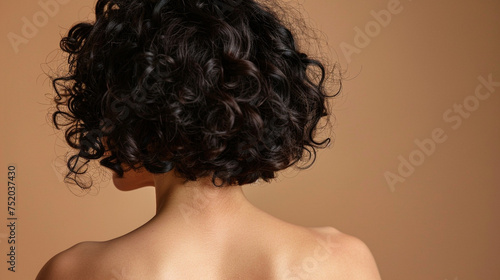 Woman with dark curly hair isolated on beige background, close up view
