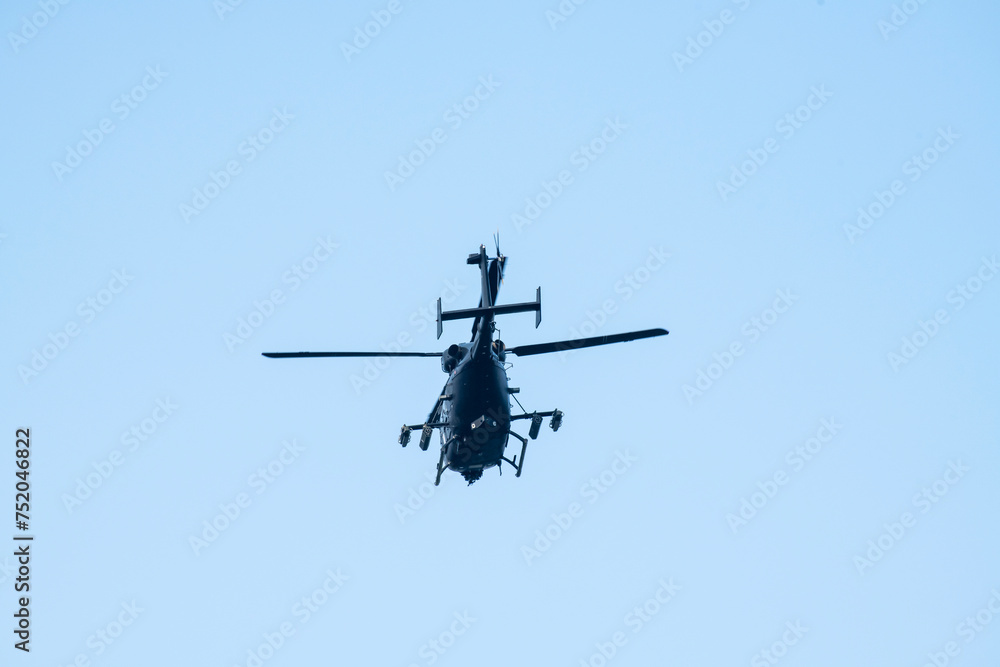 A helicopter is flying away on isolated blue sky A helicopter is flying away on isolated blue sky