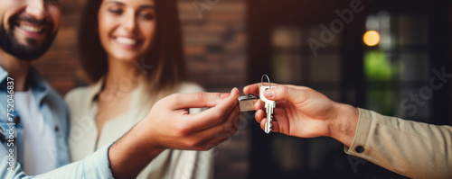Young happy millennial couple receiving keys from realtor, purchasing real estate. New house and real estate concept