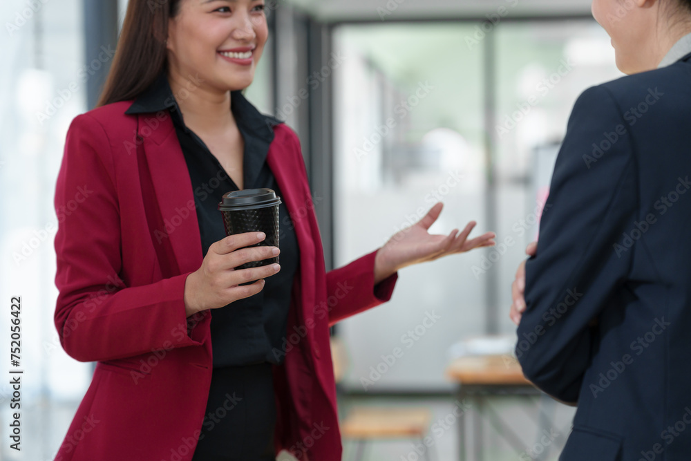 Two Asian businesswomen are discussing a new business project in the office. holding a drink Relaxing conversation, online business concept Starting a new business. Two Asian businesswomen are discussing a new business project in the office. holding a drink Relaxing conversation, online business concept Starting a new business.