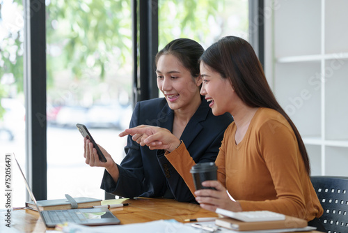 Two Asian businesswomen rejoicing over business success, smiling and expressing joy. Success in starting an online business partner teamwork concept.
