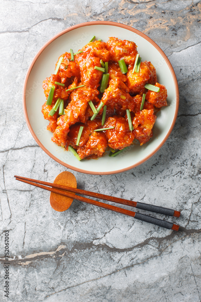 Gobi Manchurian pairs crispy cauliflower with a sweet, tangy Indo-Chinese sauce closeup on the plate on the table. Vertical top view from above