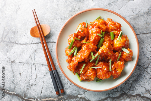 Gobi manchurian is a traditional Indo-Chinese dish consisting of fried cauliflower that’s tossed in a sweet and spicy sauce closeup on the plate on the table. Horizontal top view from above