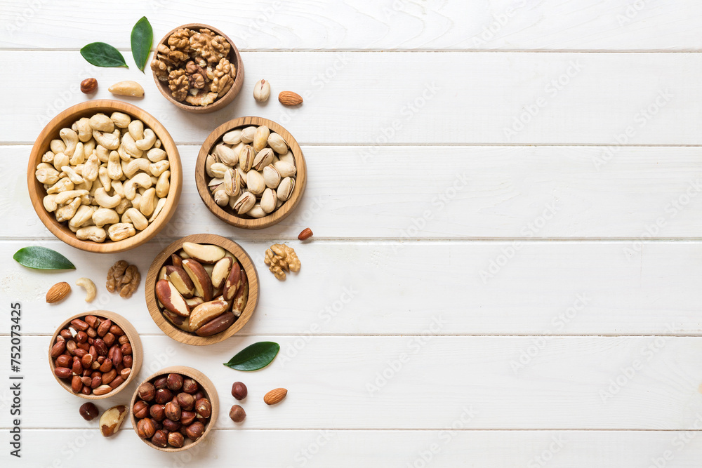 mixed nuts in wooden bowl. Mix of various nuts on colored background. pistachios, cashews, walnuts, hazelnuts, peanuts and brazil nuts