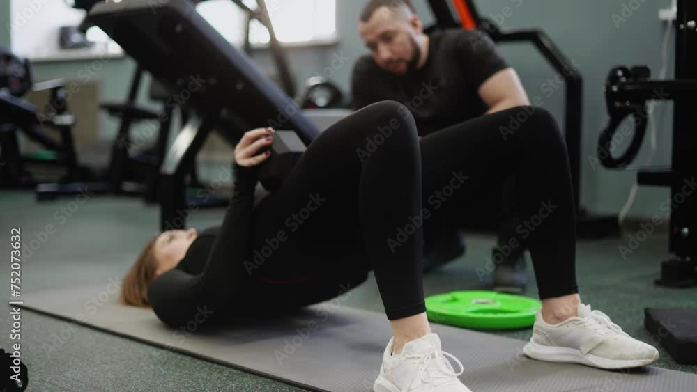 The trainer monitors and helps to perform the buttock reduction exercise correctly. Classes with an experienced coach in a gym with special equipment. The trainer monitors and helps to perform the buttock reduction exercise correctly. Classes with an experienced coach in a gym with special equipment.