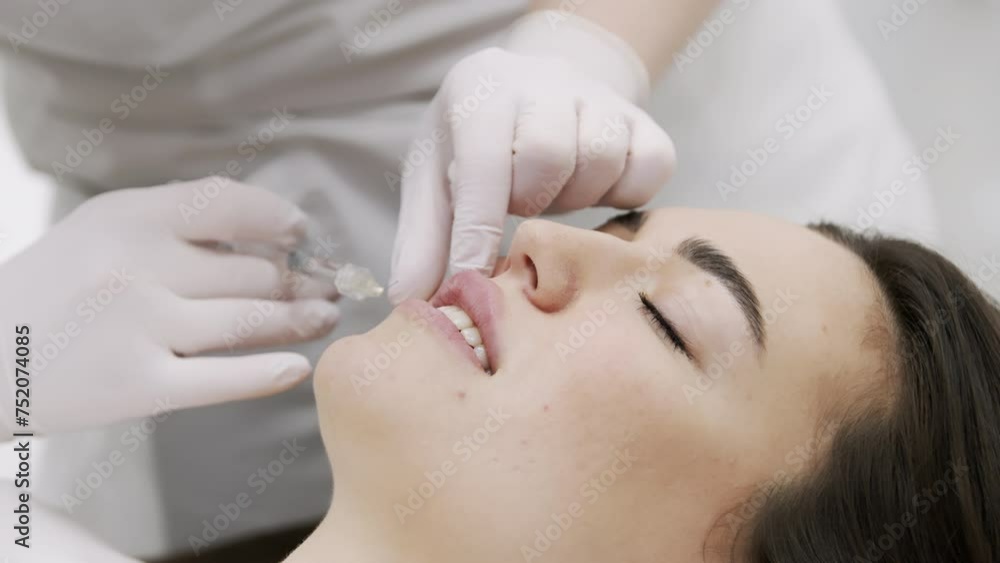 The procedure for lip augmentation and correction in a cosmetology salon. The specialist gives an injection to the patient's lips. Concept of cosmetology, cosmetic injections, and cosmetic surgery. The procedure for lip augmentation and correction in a cosmetology salon. The specialist gives an injection to the patient's lips. Concept of cosmetology, cosmetic injections, and cosmetic surgery.