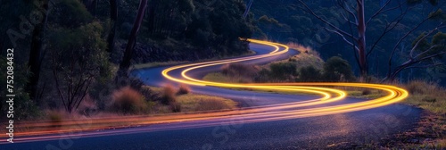 Cars light up trails on a curved paved road. photo