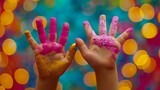 Two children's hands are covered with pink and yellow paint, creating a colorful scene.