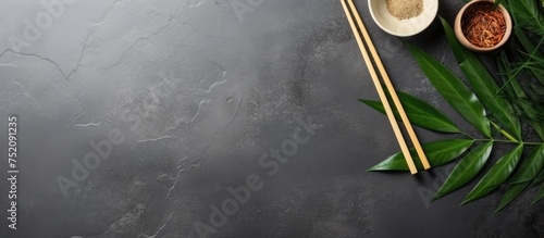 Soy Sauce and Sticky Rice Served with Chopsticks on a Textured Concrete Surface with Green Foliage Accents