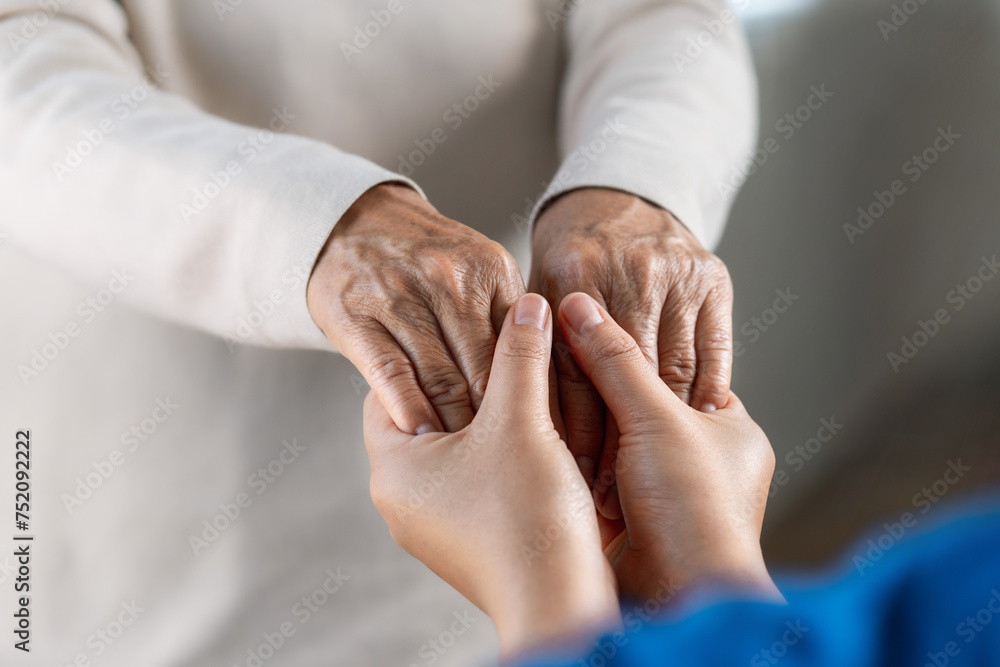 A female nurse caregiver holds hands to encourage and comfort an elderly woman. For care and trust in nursing homes for people of retirement age Caregiver helping elderly woman provides medical advice A female nurse caregiver holds hands to encourage and comfort an elderly woman. For care and trust in nursing homes for people of retirement age Caregiver helping elderly woman provides medical advice