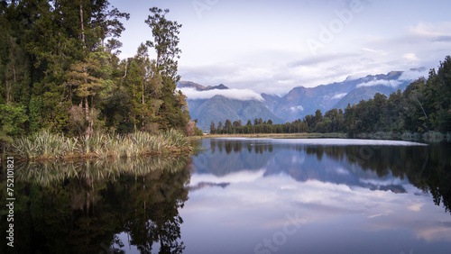 Beautiful lake surrounded by exotic forest and mountains in background during sunset, New Zealand © Peter Kolejak