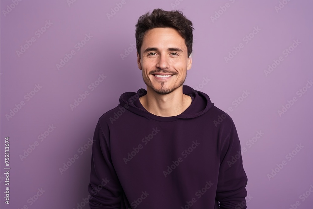 Portrait of a handsome young man smiling at camera while standing against purple background Portrait of a handsome young man smiling at camera while standing against purple background