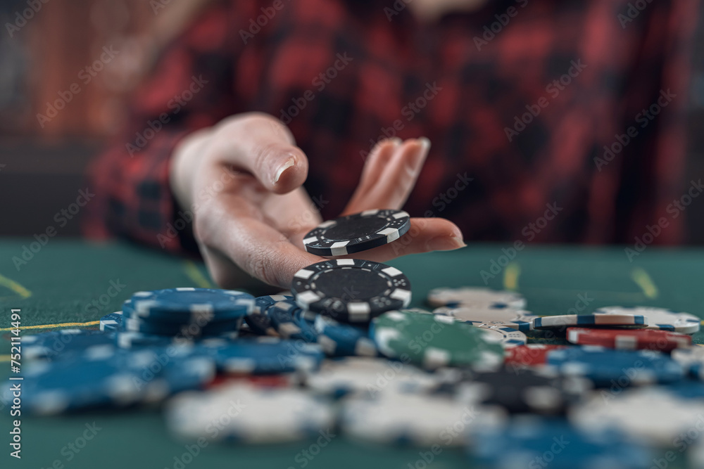 Young caucasian woman playing poker holding casino chips and makes a bet, raises