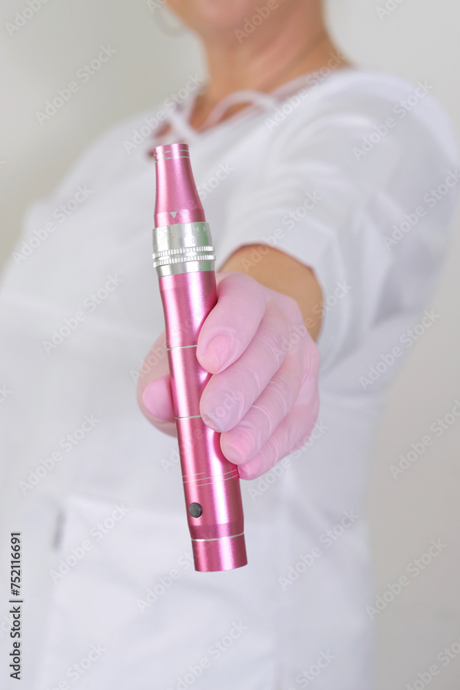 Dermatologist Holding a Pink Dermapen. A cosmetologist in a white coat is holding a dermapen, a specialized device used for microneedling skin treatment procedures. Dermatologist Holding a Pink Dermapen. A cosmetologist in a white coat is holding a dermapen, a specialized device used for microneedling skin treatment procedures.