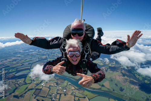 Adventurous elderly couple skydiving in tandem. Clear blue sky with soft clouds on the background