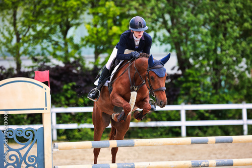 Horse show jumping horse with rider woman over the jump during a test in the show jumping competition.