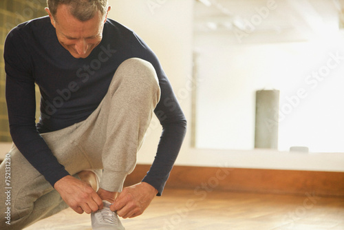 Mature Man Wearing Exercise Clothing Tying Shoelaces
