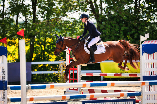 Horse show jumping horse with rider woman over the jump during a test in the show jumping competition. © RD-Fotografie