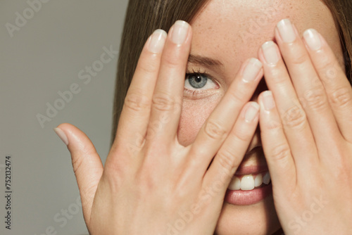 Woman with Hands over Eyes Smiling
 photo