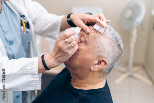 Doctor preps patient for glaucoma laser surgery with anesthetic. photo