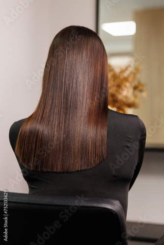 Obraz na płótnie a woman with long brown hair is sitting in a chair in front of a mirror w salonie